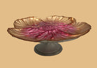 Decorative glass bowl with pink interior and gold exterior on a white pedestal against a gray background