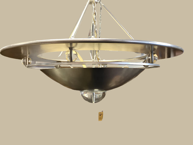 A modern chrome and lucite chandelier hanging in a store with silver color and a round shape.