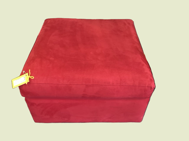 A red square ottoman with a microfiber material. It is displayed in a home furniture setting.