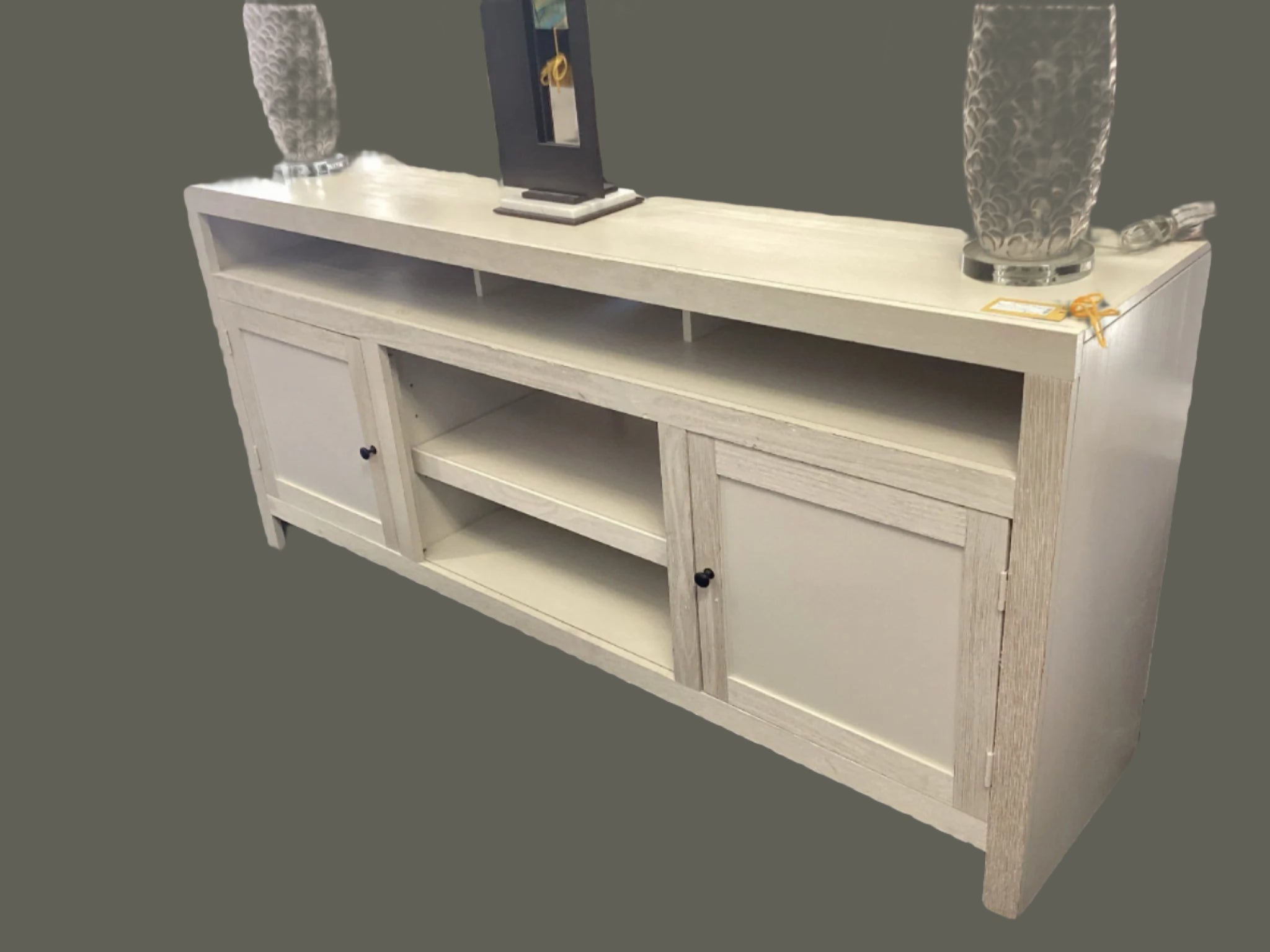 White entertainment console with decorative items on a gray background