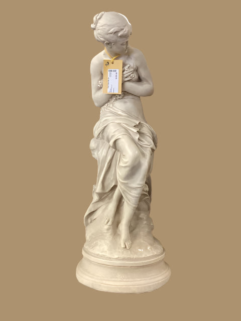A neoclassical statue of a bust, likely representing Apollo, displayed against a backdrop of painted picture frames.