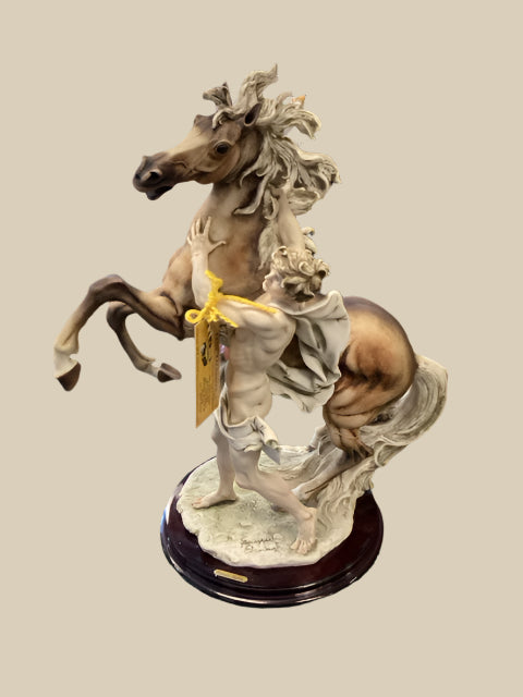 A sculpture of a man with a horse, predominantly beige in color, with the man appearing to hold the horse's reins.