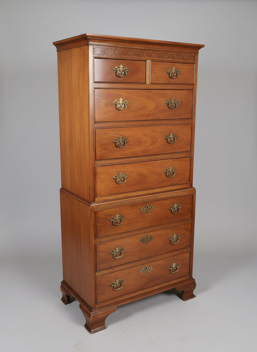 A traditional style, brown wooden tall chest with eight drawers, each featuring a metal handle, positioned against a blue wall.